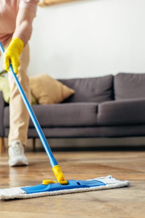 Man in homewear deep-cleaning floor with a mop.